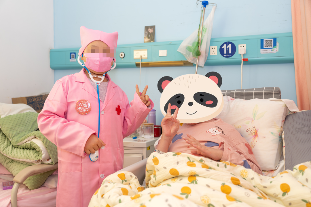 Qiqi wearing a pink doctor's coat and visiting a young patient in the hospital ward