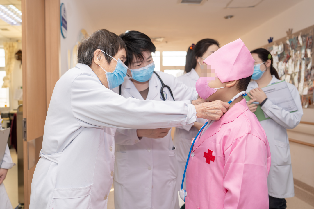 Dr. Liu Hongyan helps Qiqi adjust her stethoscope during the Doctor Experience Day