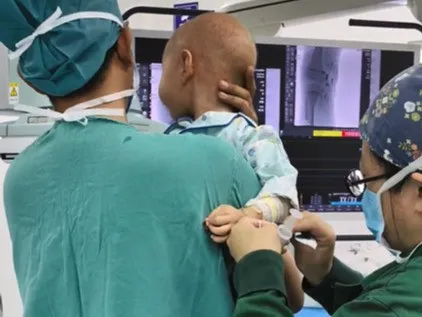 Interventional team performing intra-arterial chemotherapy — catheter precisely positioned at the ophthalmic artery