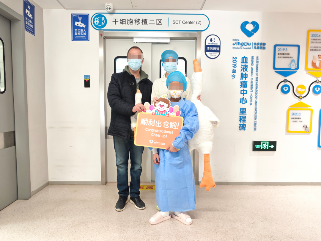 Sasha holds a large plush goose gift as his family celebrates discharge from the transplant unit